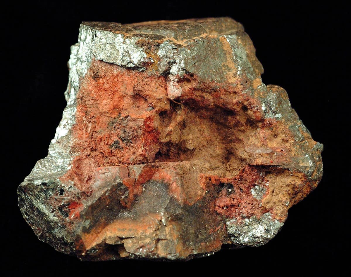 Un bloc d'hématite mêlant des plages gris acier métallique et des zones rouge brique.