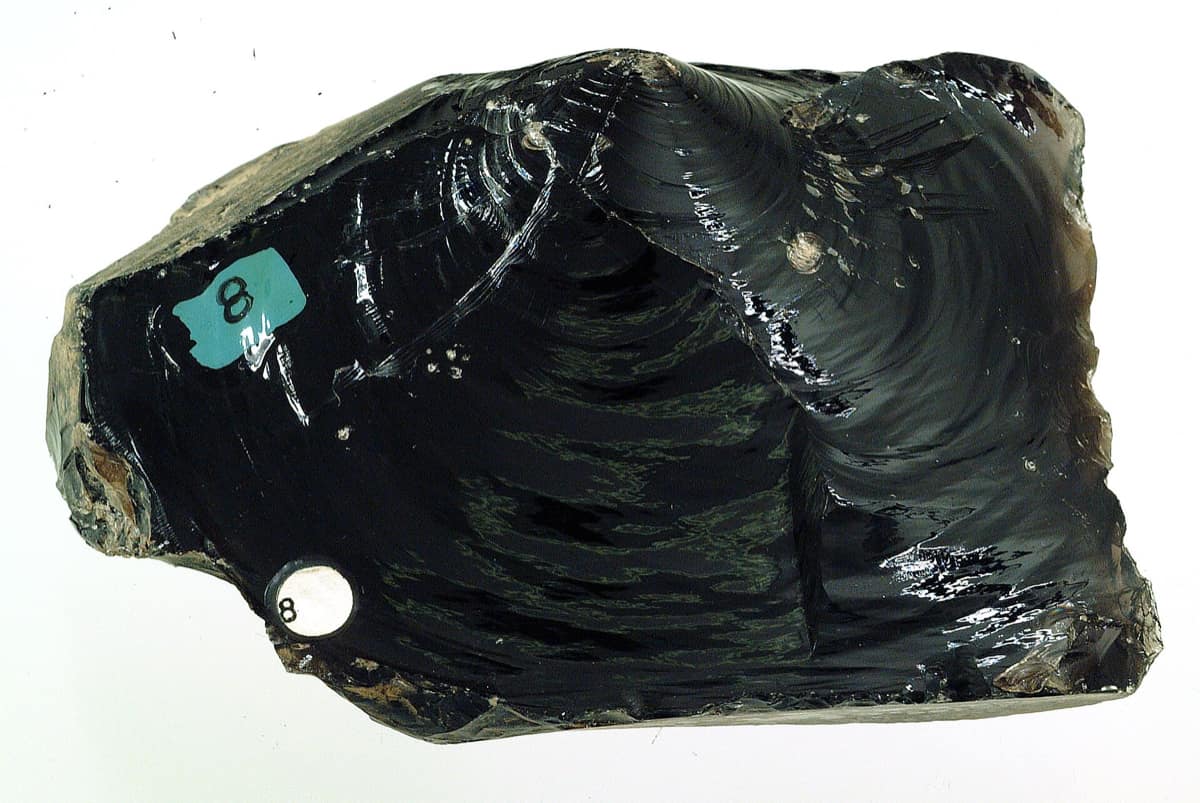 Un bloc d'obsidienne noire dont la cassure dessine des ondes concentriques lisses.